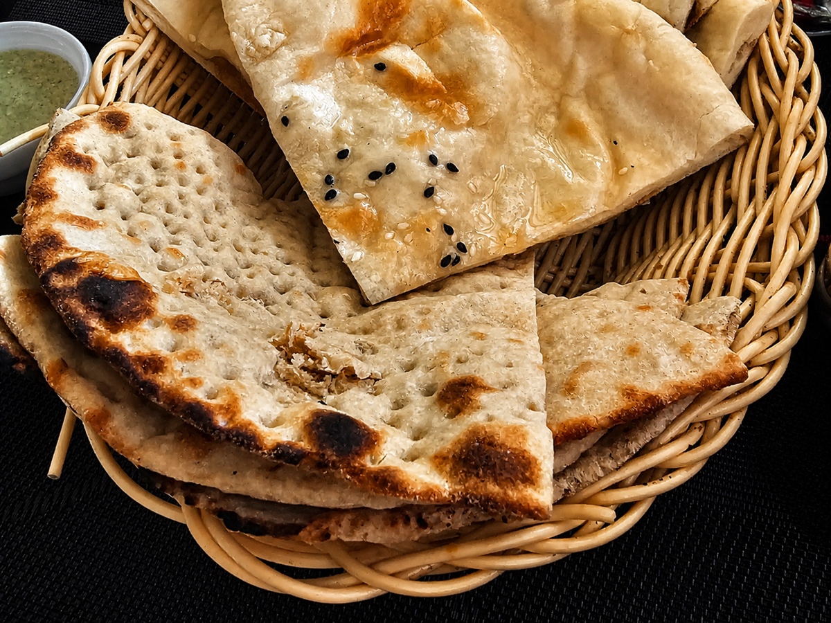 Basket of blistered naan and tandoori roti